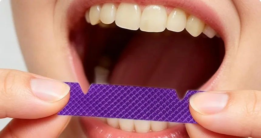 Pressing an AVEYA whitening strip onto the upper teeth