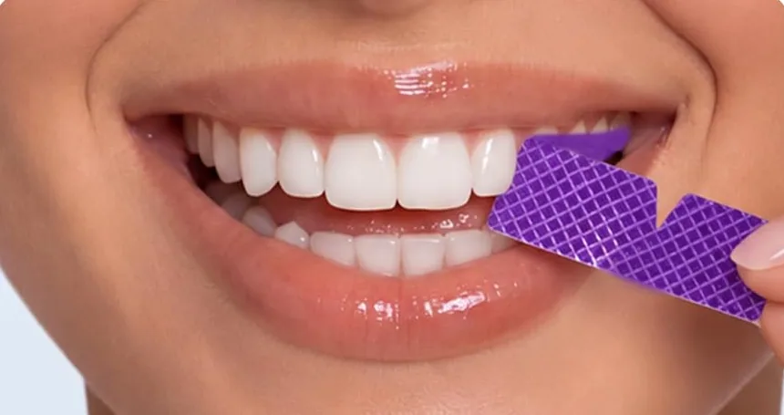 Peeling an AVEYA whitening strip off the upper teeth
